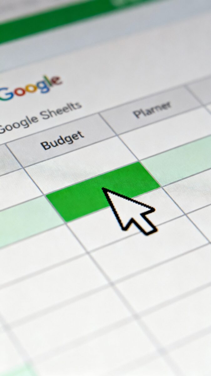 Macro shot of Google Sheets budget planner cells, green highlights, cursor hovering