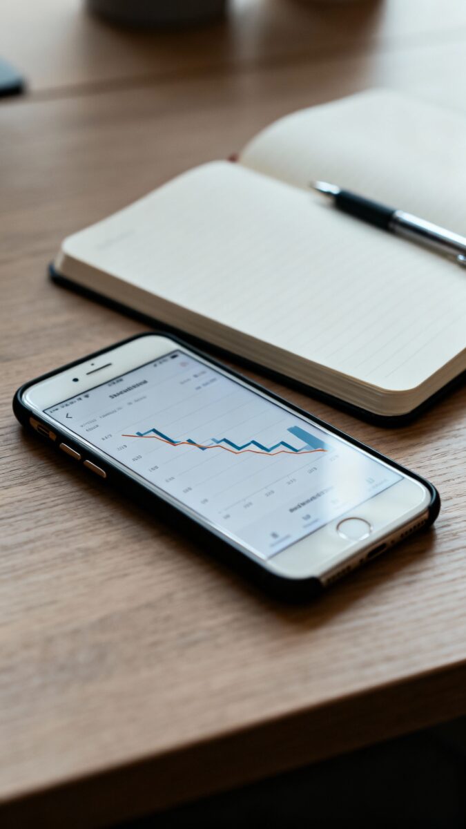 phone showing declining analytics next to open journal, pen